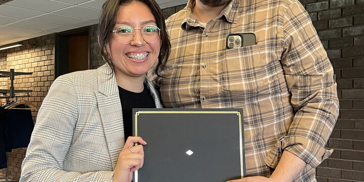 A faculty member and student pose with an award